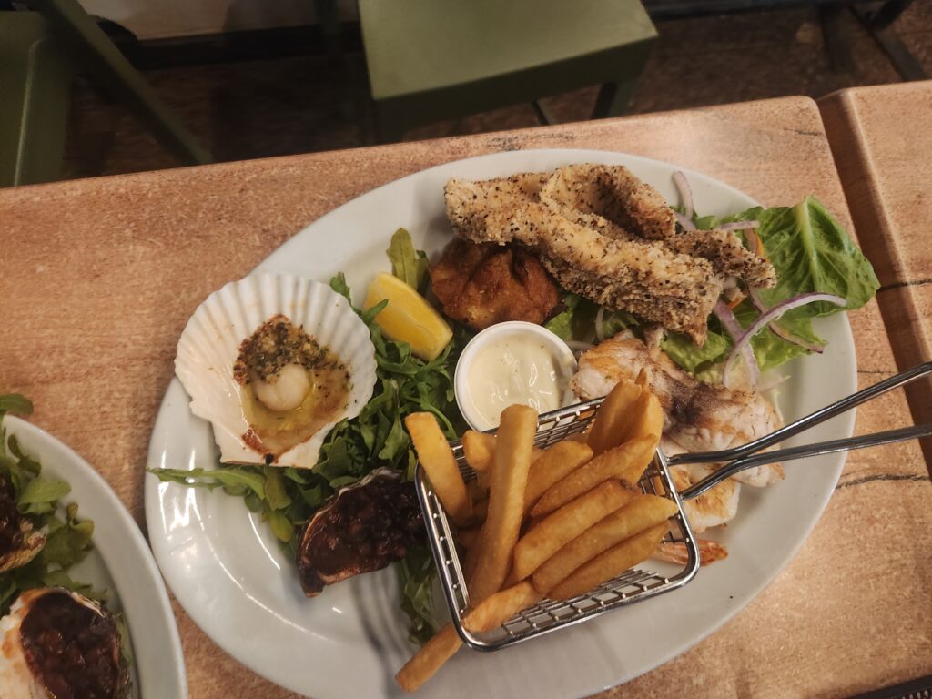 Variety of seafood and fries on a platter with dipping sauces.
