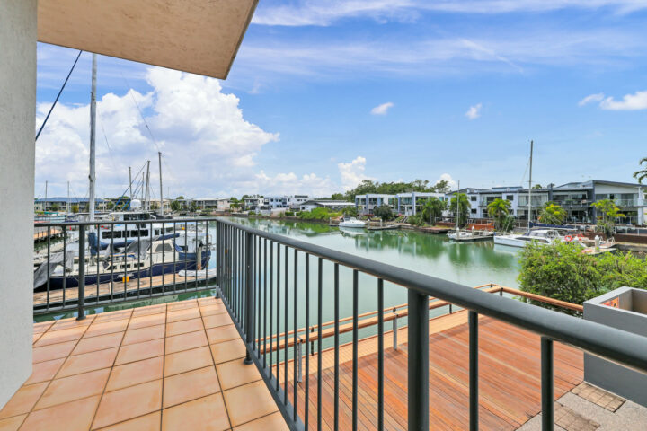 Balcony view of marina with boats, blue sky, and clouds.