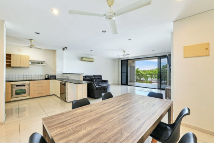 Modern open-plan kitchen and living area with dining table and large windows.