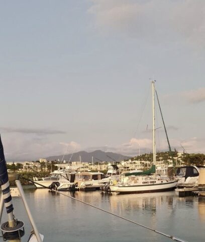 Boats docked in a marina with mountains in the background.